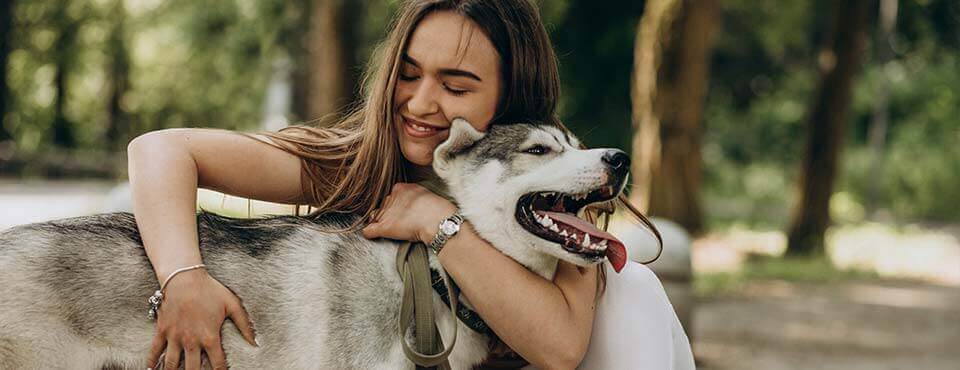 Eine Frau umarmt einen glücklichen Husky.